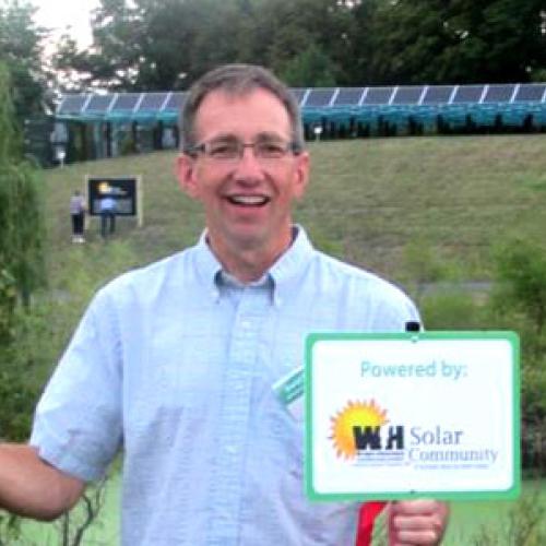 David stands in front of the WHE community solar project with his yard sign