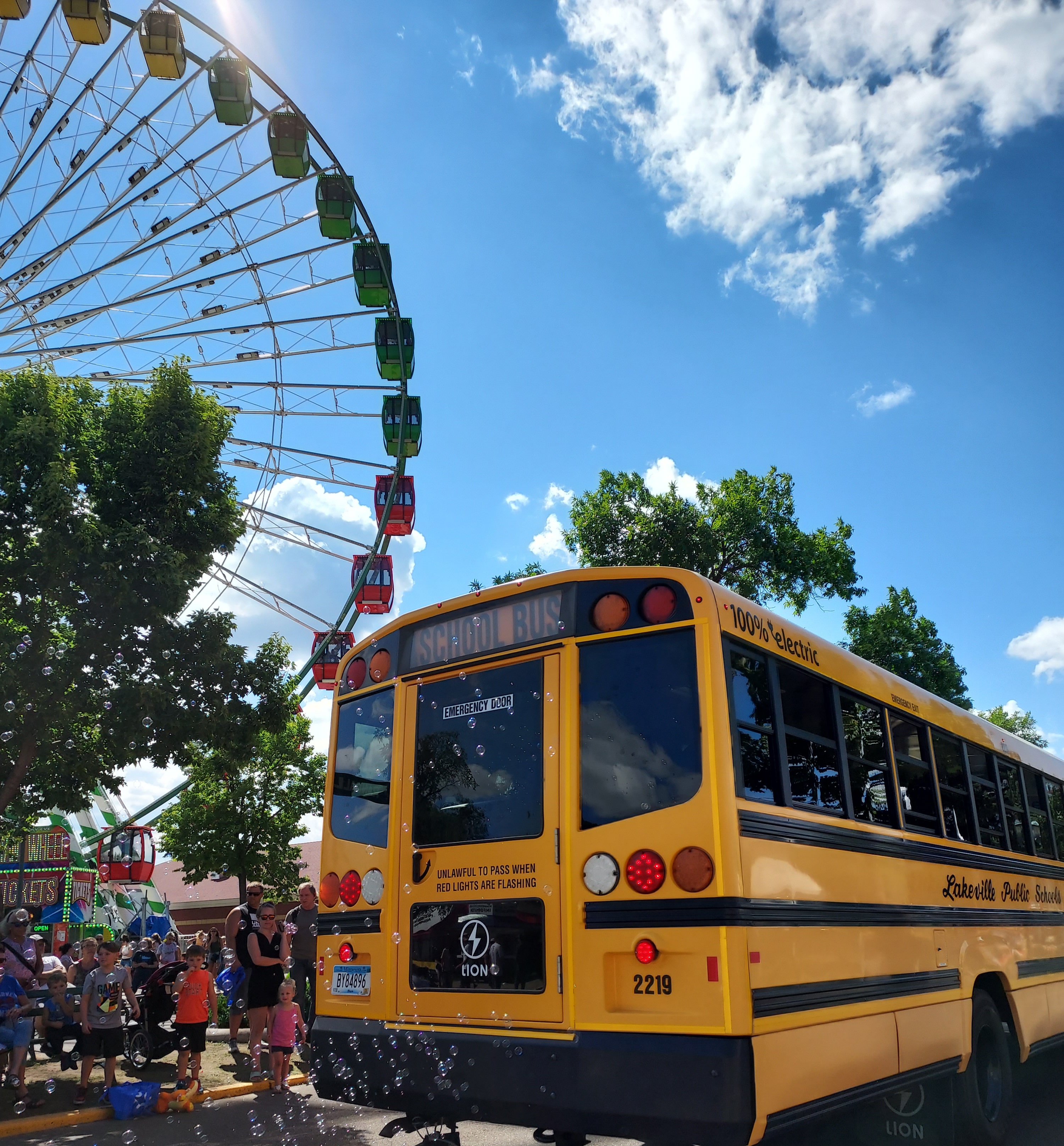 Electric school bus by a ferris wheel