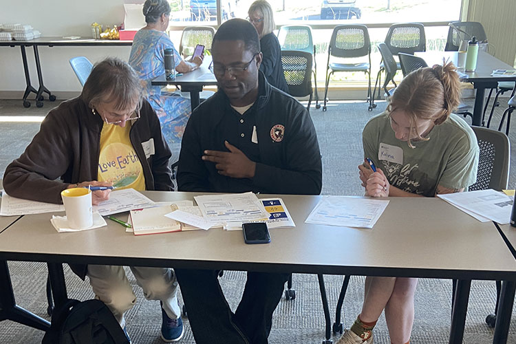 Three people, CEA ambassador sitting in the middle, discussing paper work