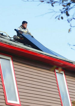 A worker for All Energy Solar carefully placed a panel onto the roof of the Art House B&B. It took the company about two days to install the panels