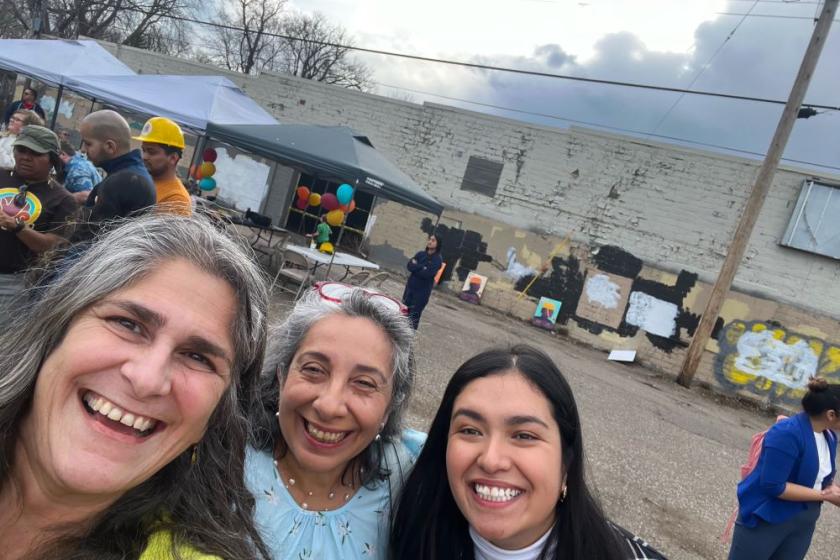 Three women stand together smiling in a selfie post. 