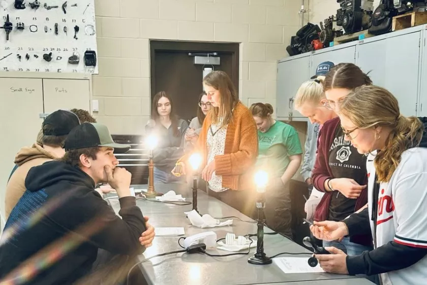 Heidi Auel stands in a science classroom, surrounded by students. 
