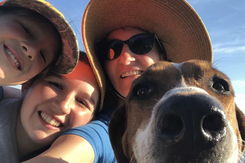 A woman takes a close-up selfie with two children and a dog. 