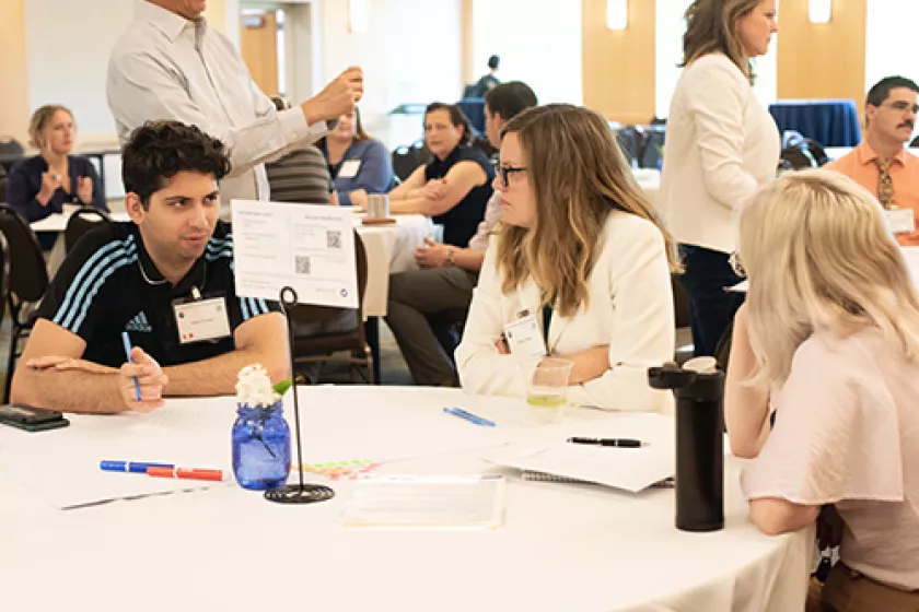 Three people sitting at a round table at a networking event. 