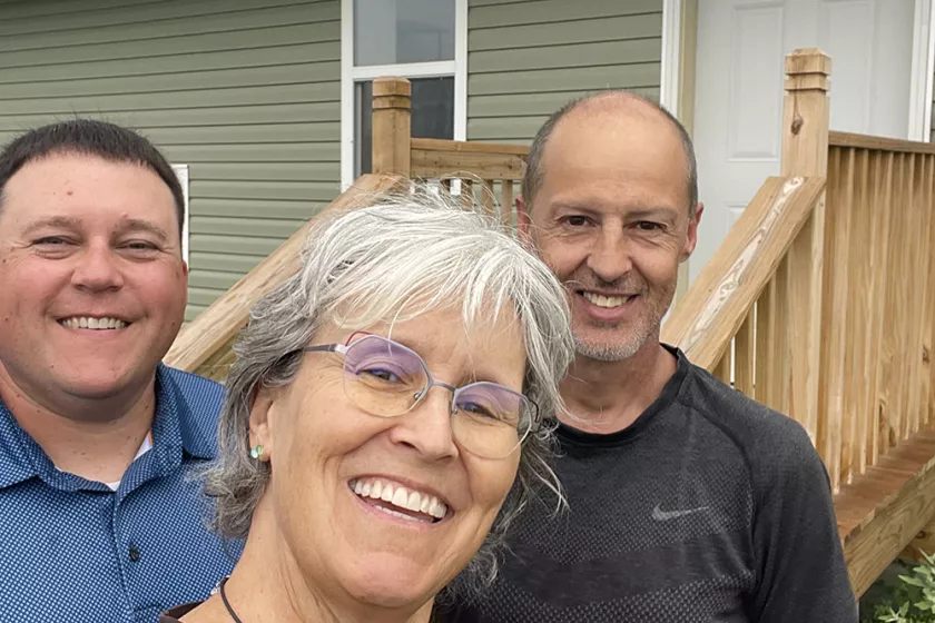 Erika and two men outside of a hempcrete house
