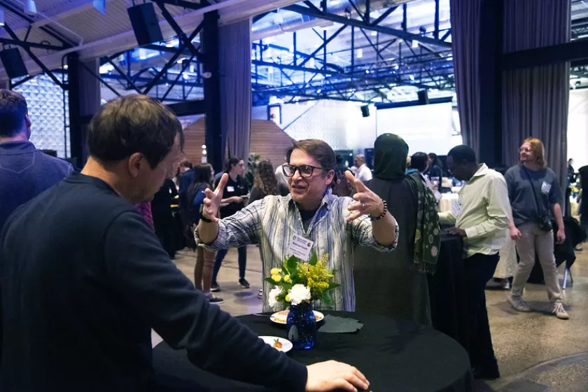 Attendee with glasses standing at black table, networking