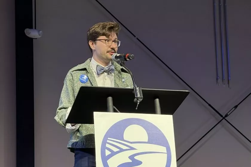 Aaron Backs stands at a podium at the CERTs Annual Metro Event. 