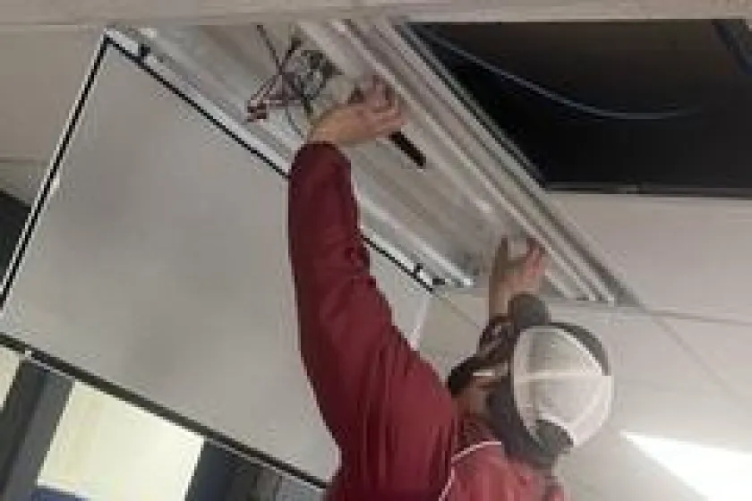 Person in a red jacket installing LED into the ceiling