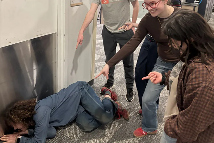 people pointing to person checking under door