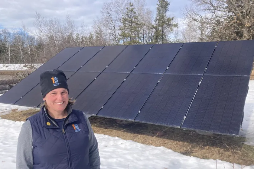 Brooke Tapp of One Roof Community Housing stands in front of a large ground-mounted solar array in Duluth.