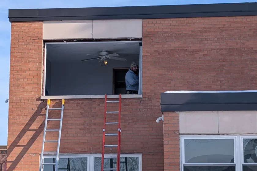 Man inside of a brown building seen from an open window. 