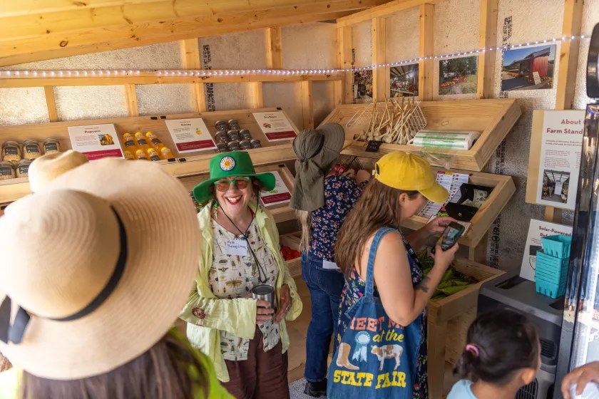 Four women examine products and chat in a small shed.