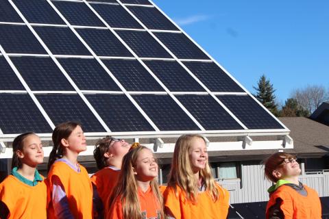 Students smiling under solar panel