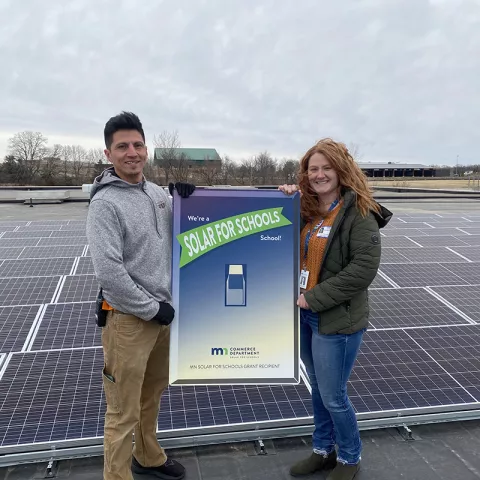 Two people holding a solar for schools sign
