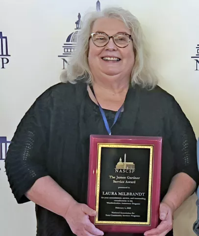 Laura Milbrandt posing while holding the award