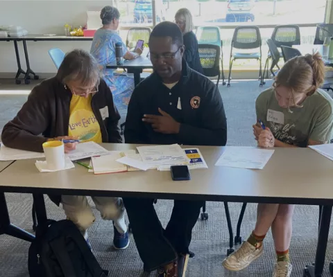 Three people, CEA ambassador sitting in the middle, discussing paper work