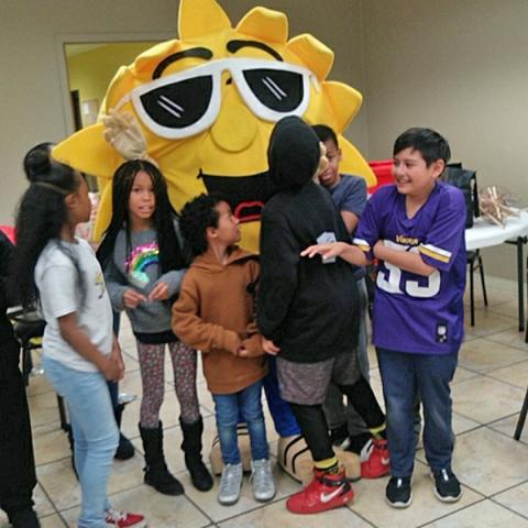 children standing with a sun mascot