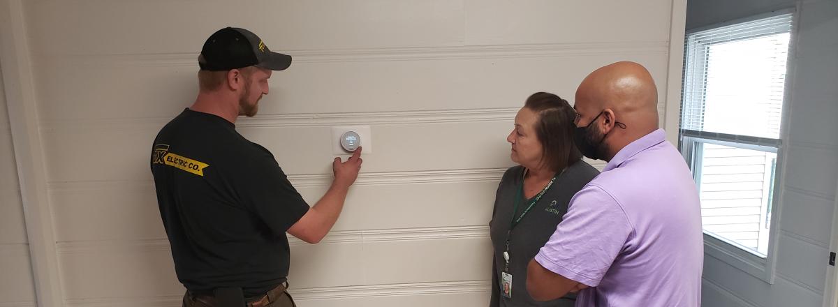 Kelly Lady with HRA staff observe an installation of thermostat with Fox Electric
