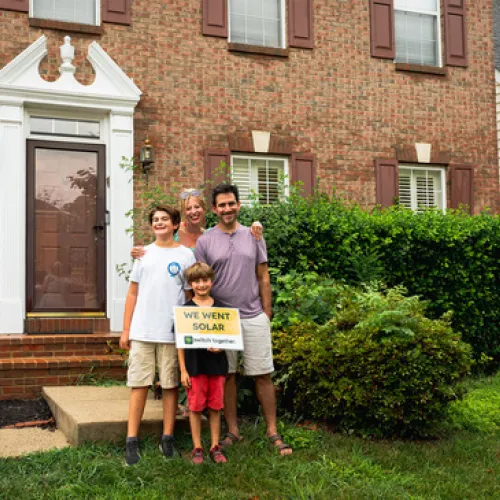 Family of three posing in front of a house