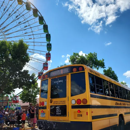 Electric school bus by a ferris wheel
