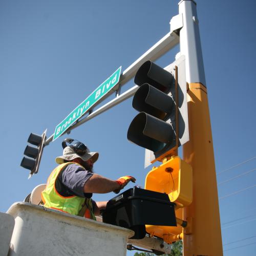 A worker installs LED traffic signals on Hennepin County's Brooklyn Boulevard.