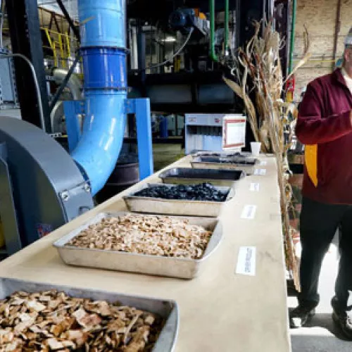 Don Fosnacht, NRRI associate director of the Renewable Energy Initiative, describes the process of converting wood (foreground) into compact briquettes that can be used in coal-fired power plants. Photo by Bob King, Duluth News Tribune