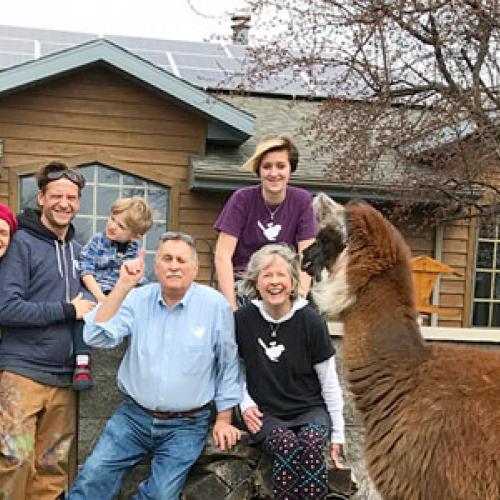 Ron and Kathy Gray, front right, along with (left to right) their daughter Miranda, son-in-law Scott, and grandchildren Murdock and Gwendolyn, pose with their rooftop solar energy system. Llamas from their family business join in the fun.