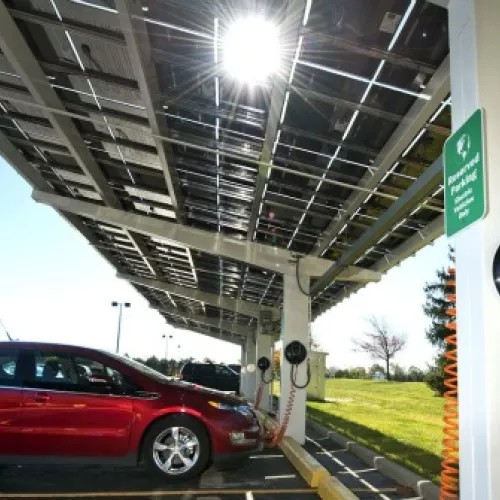 vehicles parked under an awning with ev chargers mounted on pillars
