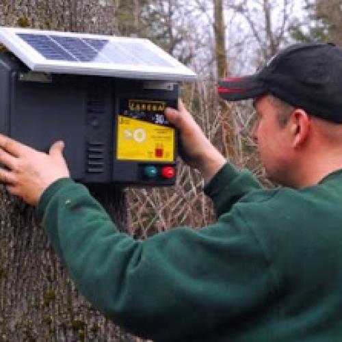 Installing a solar electric fence charger to keep deer away (Photo by Pat Lefemine)