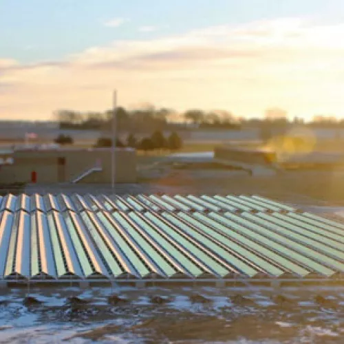 The sun rises over Hutchinson’s new solar PV project, the largest on a landfill in Minnesota, and the first ballast-mounted on a brownfield. Hutchinson’s wastewater treatment facility, the recipient of the array’s electricity, can be seen in the background