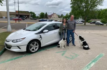 Couple with dogs charging their electric vehicle in Wadena.