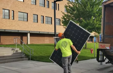 person carrying solar panel to Edina school