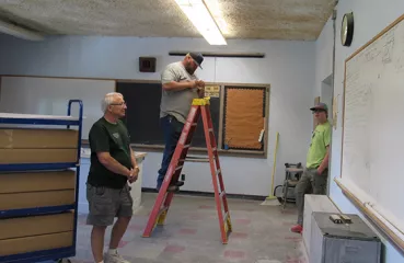 People installing lights in old classroom