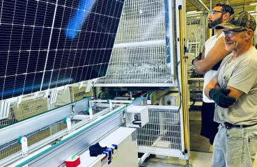 People looking at a solar panel manufacturing line
