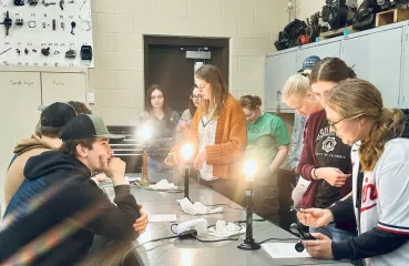 Heidi Auel stands in a science classroom, surrounded by students. 