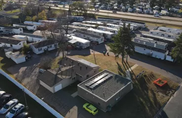 An aerial view of a few dozen manufactured homes and two with solar panels on top.