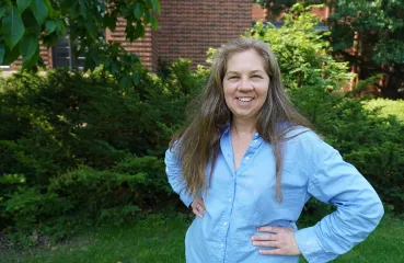 Maggie Kozak stands outside smiling, with her hands on her hips