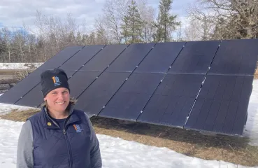 Brooke Tapp of One Roof Community Housing stands in front of a large ground-mounted solar array in Duluth.