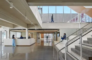 Large atrium with windows and stairs. A few people are roaming around.