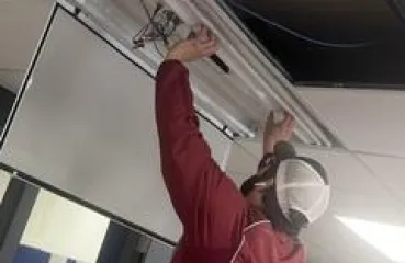 Person in a red jacket installing LED into the ceiling