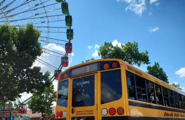 Electric school bus by a ferris wheel
