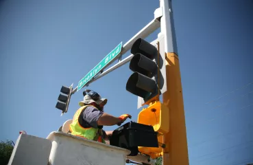 A worker installs LED traffic signals on Hennepin County's Brooklyn Boulevard.