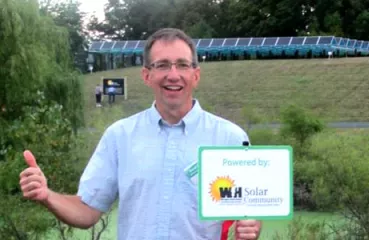David stands in front of the WHE community solar project with his yard sign