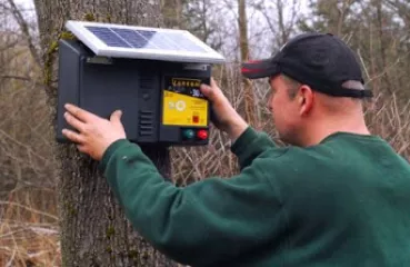 Installing a solar electric fence charger to keep deer away (Photo by Pat Lefemine)