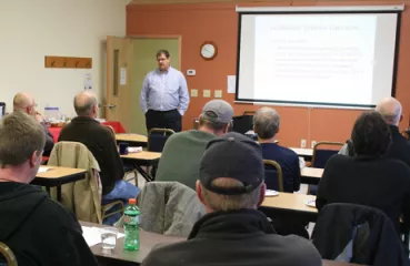 person gives presentation in front of group sitting at tables