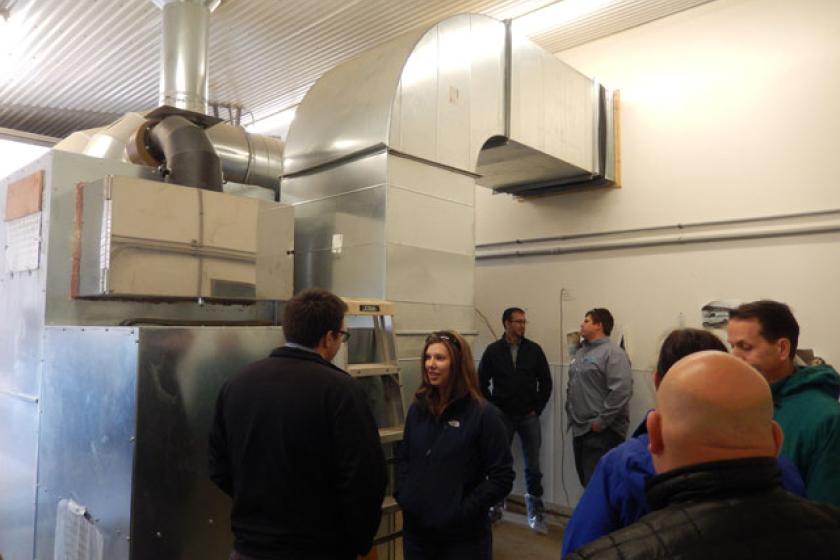 Tour participants take a close look at the biomass furnace heating a barn at Viking Company, a broiler chicken growing operation in Albany, MN.
