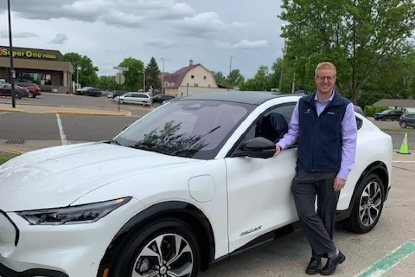 Attendee stands in front of white electric vehicle.