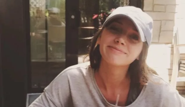 Rau looks casual as she sits outside smiling over a beverage.