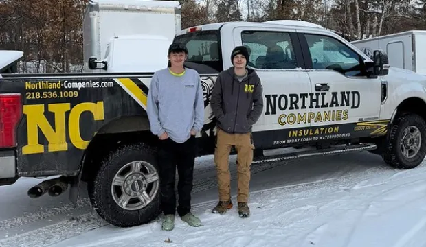 Two Northland crew members posing in front of a pickup truck
