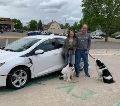 Couple with dogs charging their electric vehicle in Wadena.